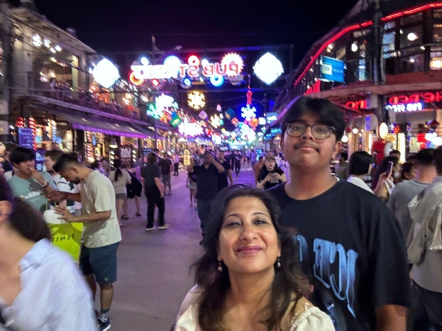       Two people posing on a busy street under colorful lights.
  