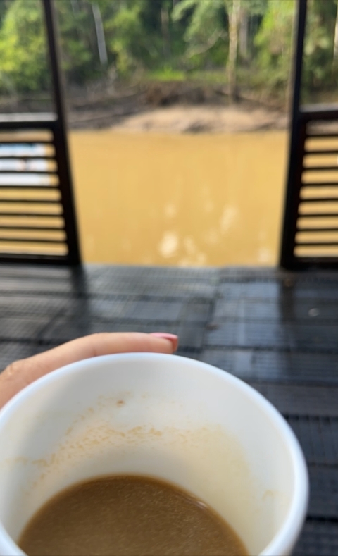 A blurry image with a hand holding a cup and a wooden background.