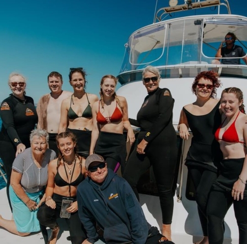      A large group of people posing on a boat, likely on a tour.
  