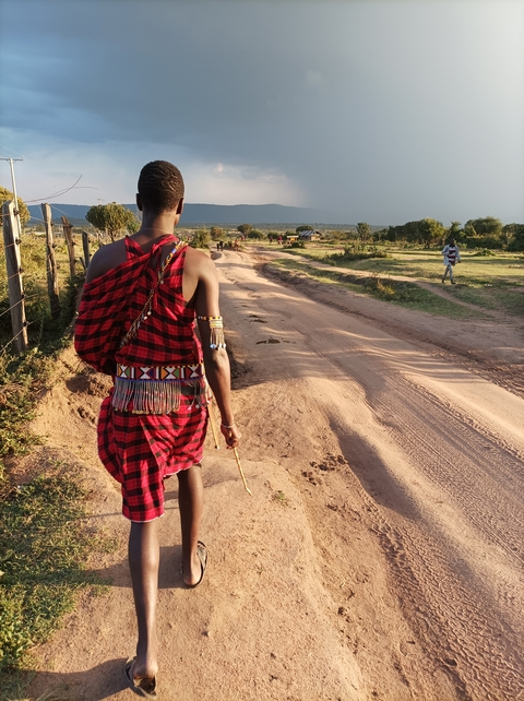 A person in traditional attire walking along a dirt road.