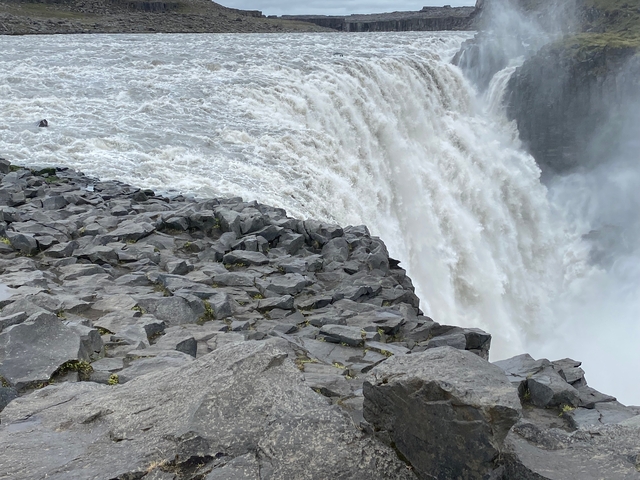 A close-up view of a powerful waterfall with rocky terrain.
