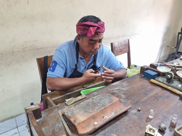       Man working on craftsmanship, concentrating on a piece in his hands.
  