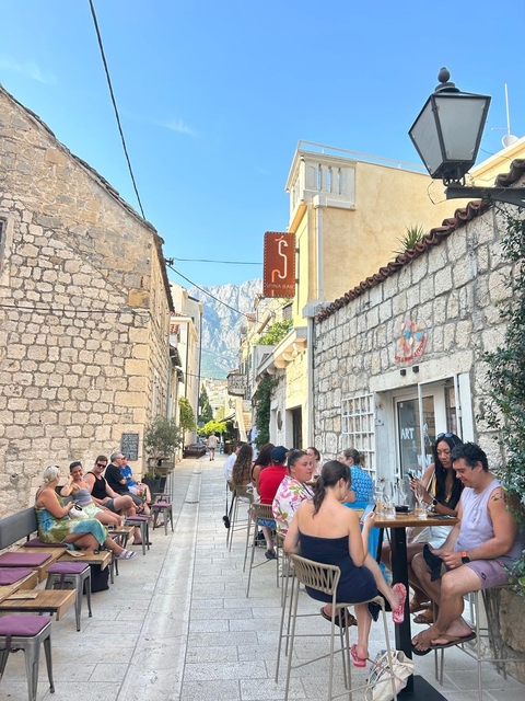 People sitting in a historic, charming stone-paved street.
