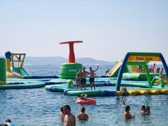 People enjoying an inflatable water park at sea.
