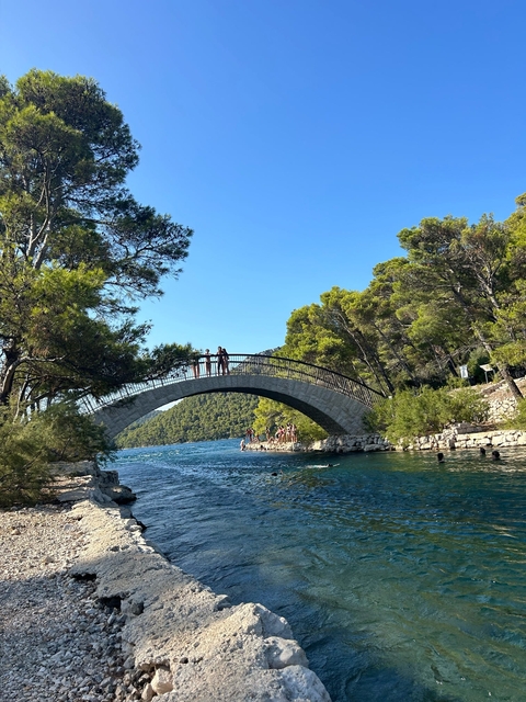 Picturesque stone bridge over a clear blue waterway.