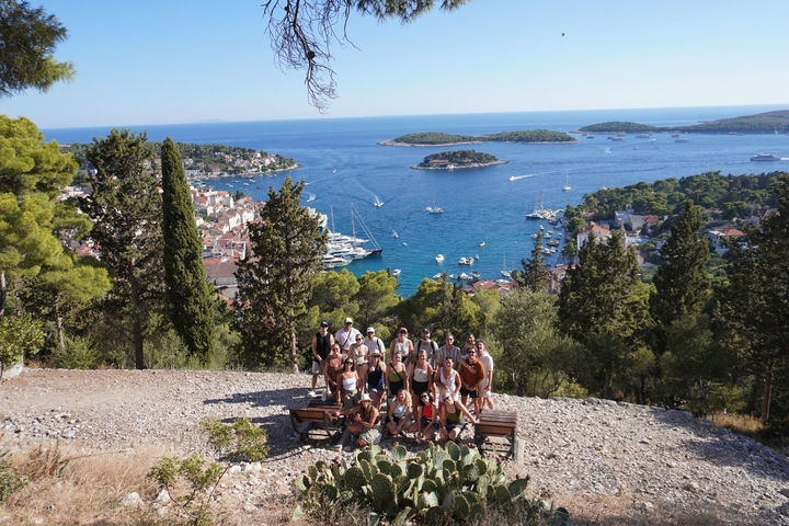 Group of people posing with a view of the sea and islands.