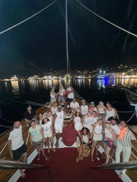 Group of people on a boat at night with city lights in the background.