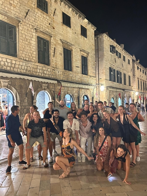 Large group of people posing in front of a historic building at night.