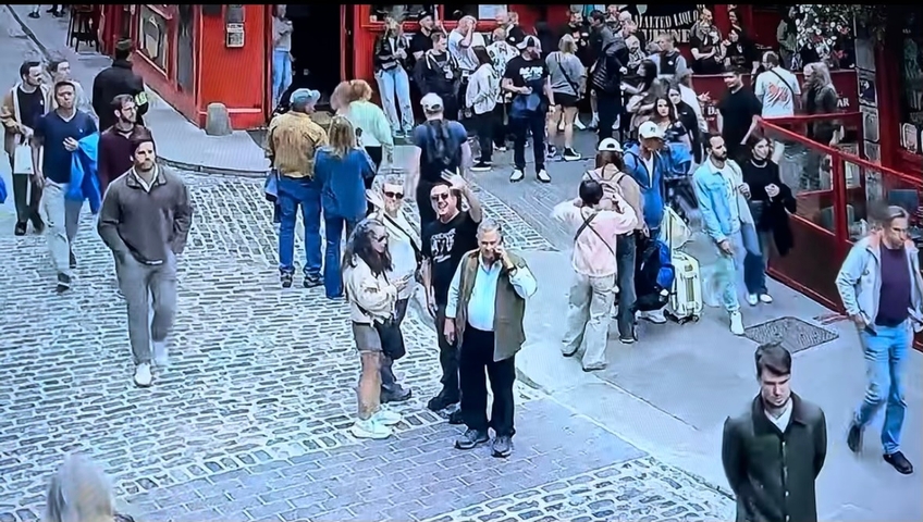       People walking in a busy cobblestone street.
  
