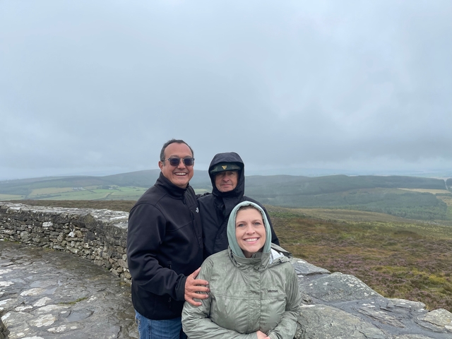       Group of people in windy weather at a hilltop with cloudy sky.
  