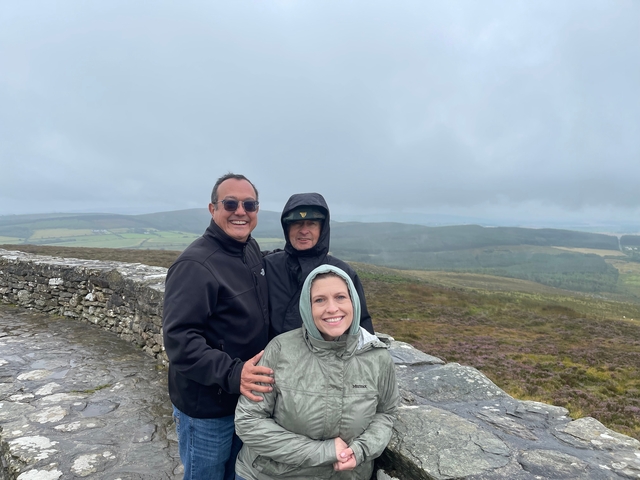       Group of people on a stone path, observing a scenic view.
  