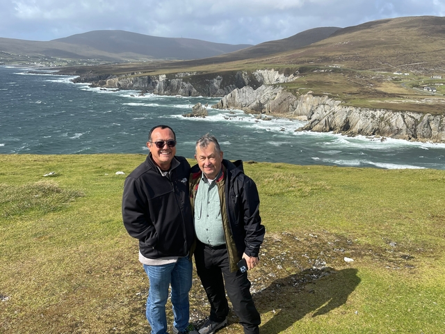 Two people taking a picture at a high elevation overlooking hills.
