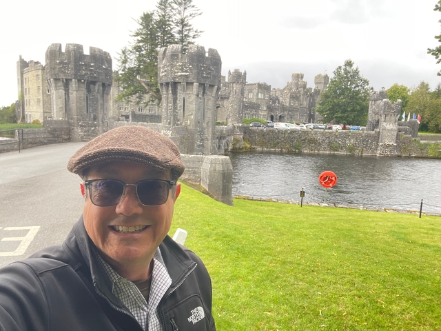      Person taking a selfie with a castle and moat in the background.
  