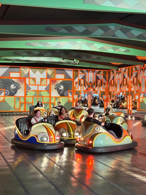       People riding bumper cars indoors.
  