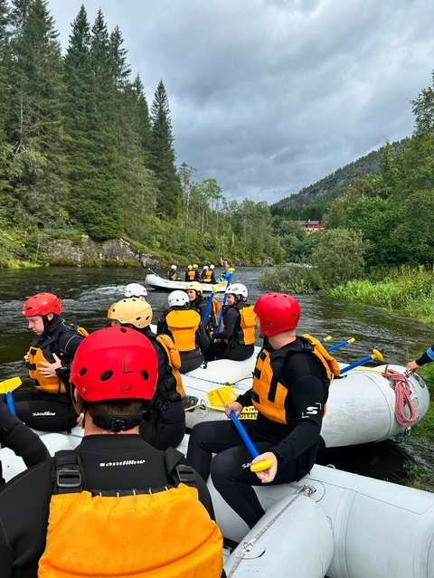       People in helmets rafting on a river.
  