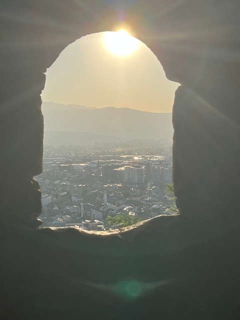 View through a gap showing a cityscape at sunset.