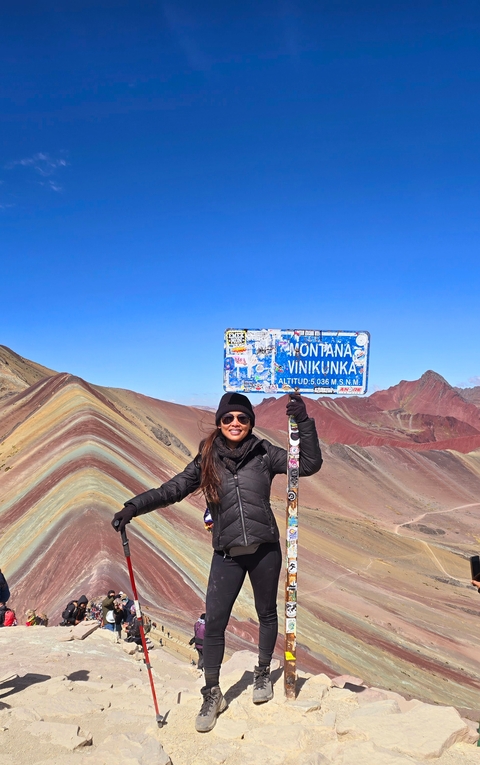       Person at Montaña Vinicunca with colorful mountain landscape in the background.
  