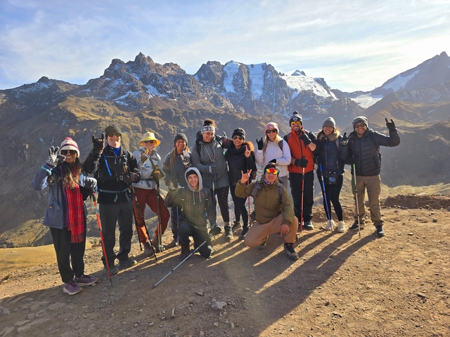       Group of people posing with trekking gear in a mountainous area.
  