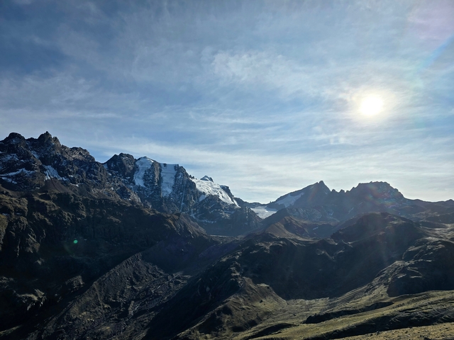       Mountain range with a sunlit peak and clear skies.
  
