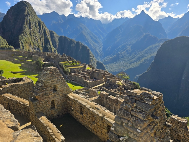       Machu Picchu ruins with visitors, surrounded by mountains.
  