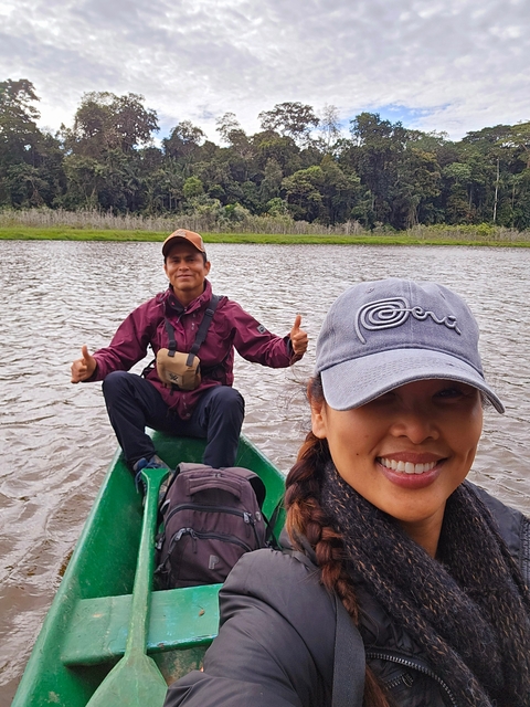       Two people smiling in a small boat in a river.
  