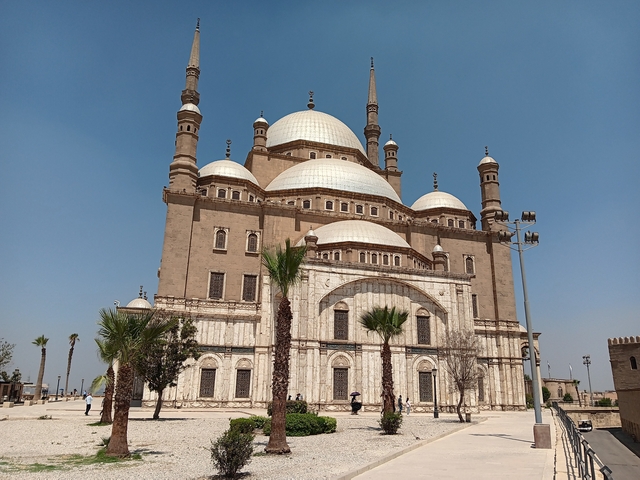 Large historic mosque with multiple domes and minarets under clear sky.