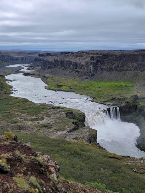 Aerial view of a waterfall and river in a canyon.