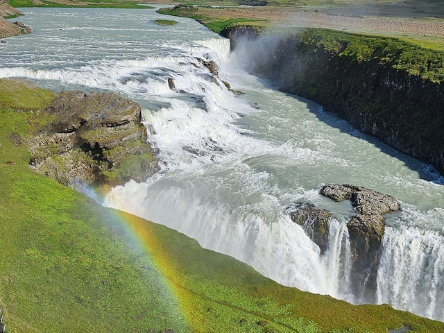 Waterfall with a visible rainbow over the landscape.