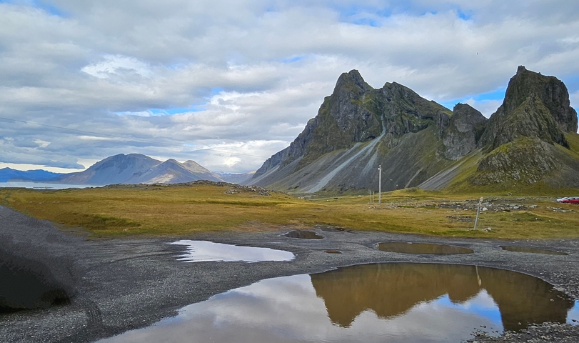 Mountains with a clear sky and water puddles reflecting the sky.