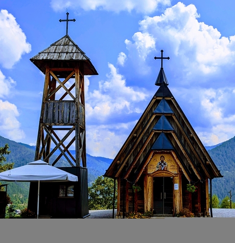Wooden church with a bell tower against a cloudy sky.