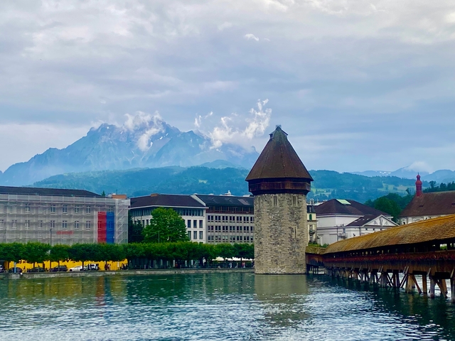 Historic tower and bridge with mountains in the background.