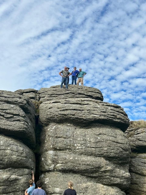 Group of people posing on top of rock formations under a blue sky.