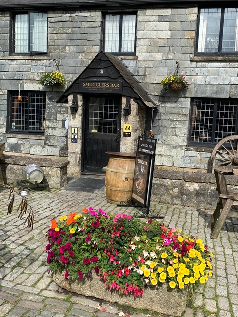 Old inn with cobblestone pavement and colorful flowers.