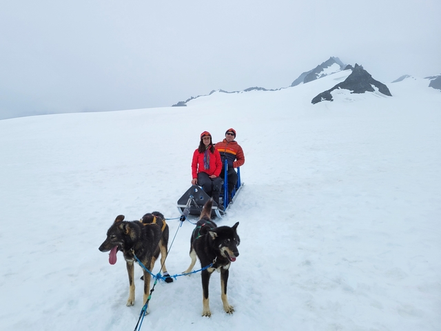 People on a dog sled in a snowy arctic setting.
