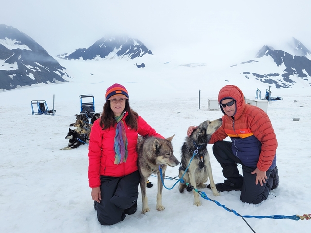       Couple with sled dogs on a snow-covered mountain.
  