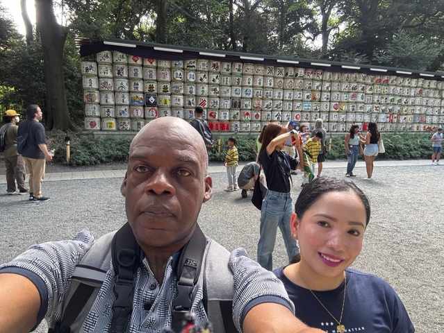       People in front of a wall with traditional sake barrels.
  