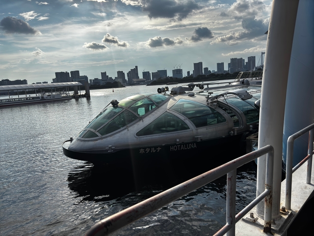Futuristic boat docked with a city skyline in the background.