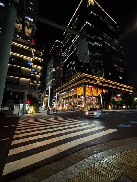 Street scene at night with illuminated buildings.