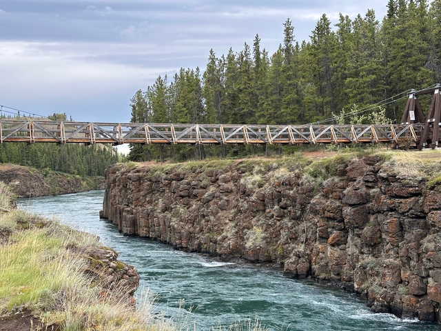 A bridge over a rocky canyon with a river.