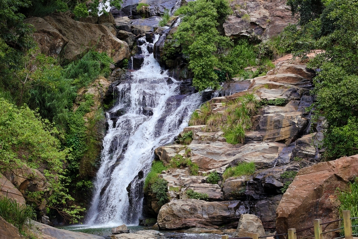 A small waterfall cascading over rocky terrain surrounded by greenery.