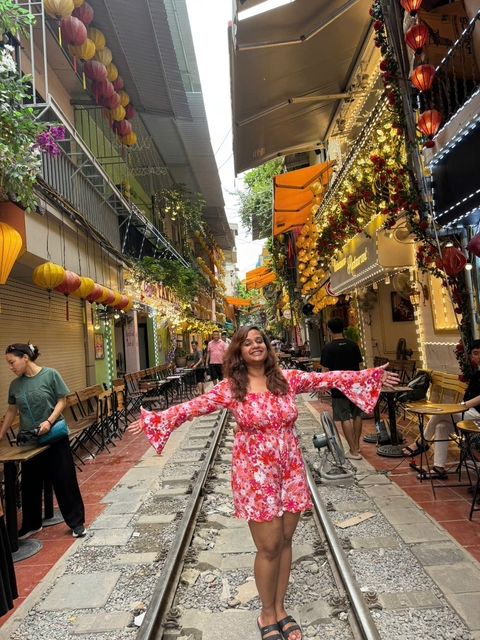       A woman in a vibrant street lined with shops and hanging decorations.
  
