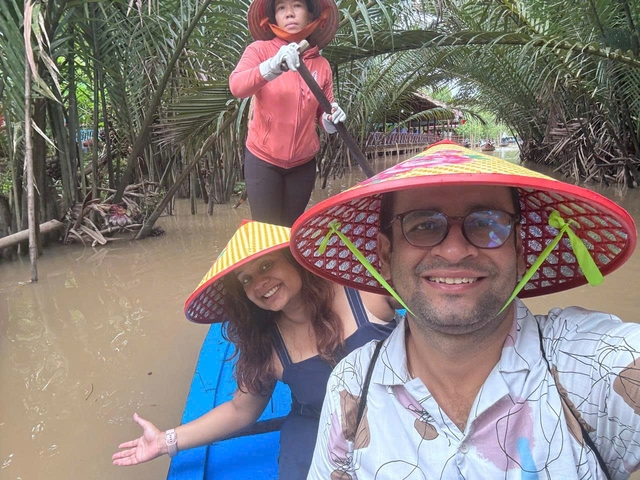       People in a boat enjoying a ride through a narrow waterway with lush vegetation.
  