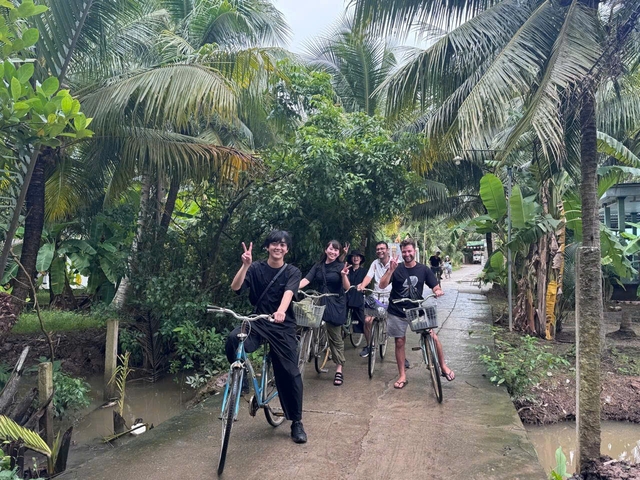       Group of people on bicycles on a pathway surrounded by tropical plants.
  