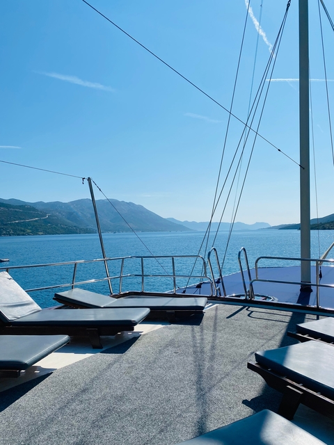 View from a boat deck overlooking a serene waterbody with mountains.