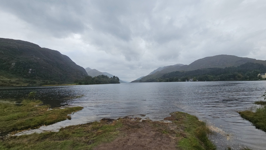 A lake with mountains in the background under a cloudy sky.