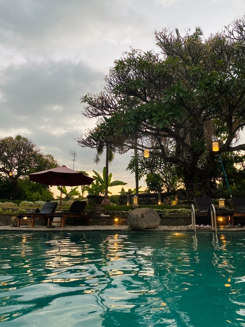 Poolside lounge chairs with garden and decorations at dusk