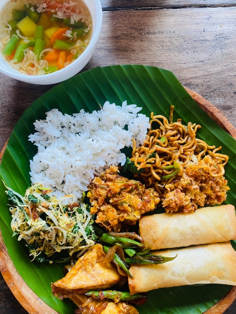 Plate of rice, noodles, and other Indonesian food on a banana leaf