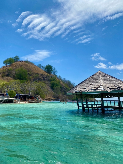 Waterside hut with clear turquoise waters and a hill
