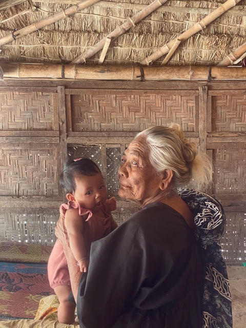 Elderly woman holding a baby against a woven background