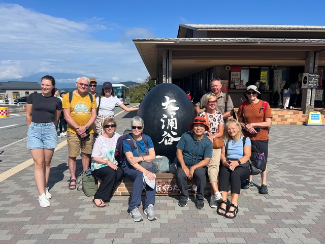       Group posing with a large stone outside a building.
  